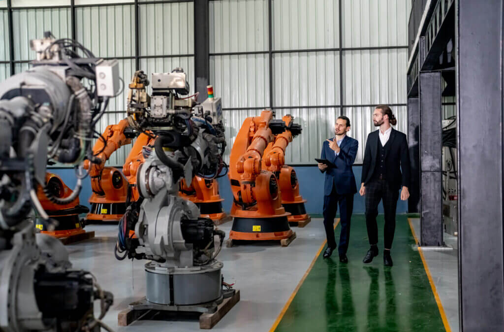 Businessman pointing toward machinery while walking by coworker at industry